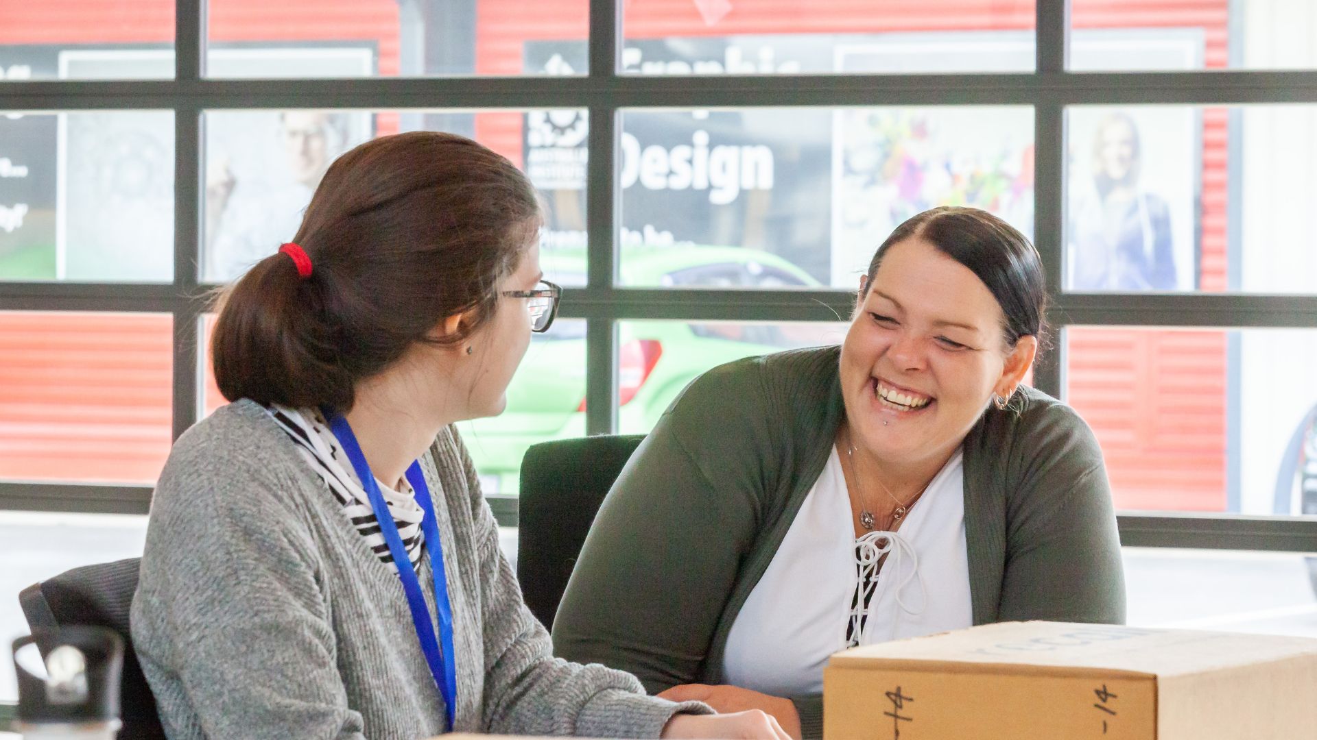 Trainee and Tammie Usher sitting at a desk looking at each other