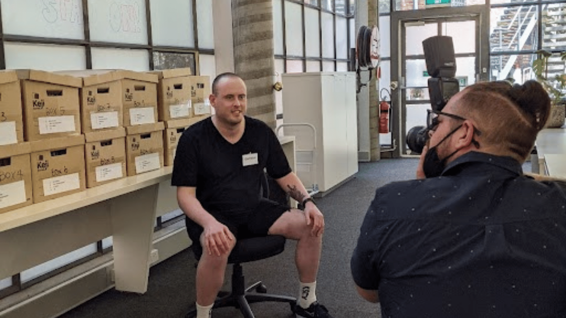 Jigsaw trainee Daynah sits on an office chair having his photo taken