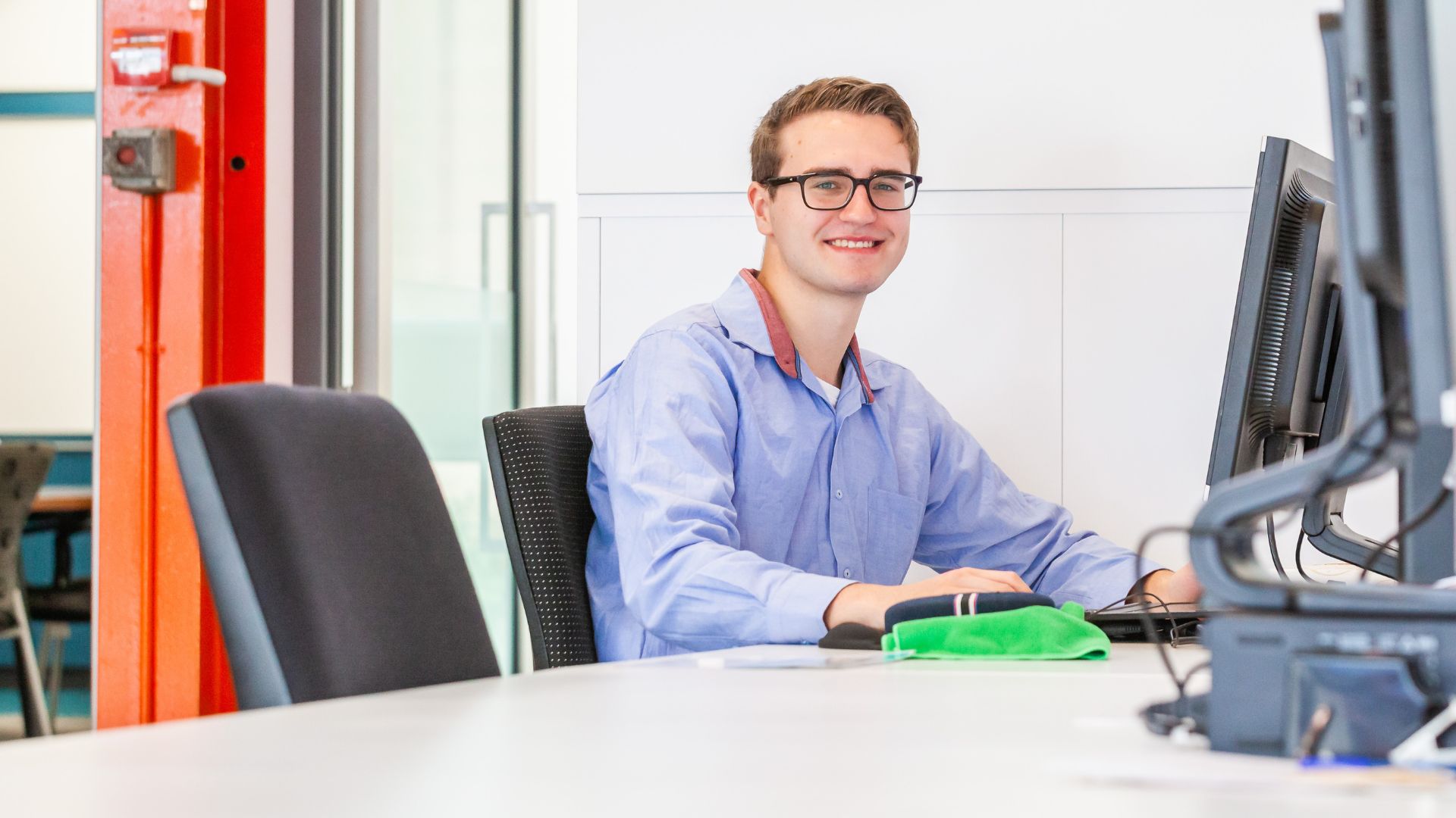 Jigsaw trainee sat in front of desk smiling at camera